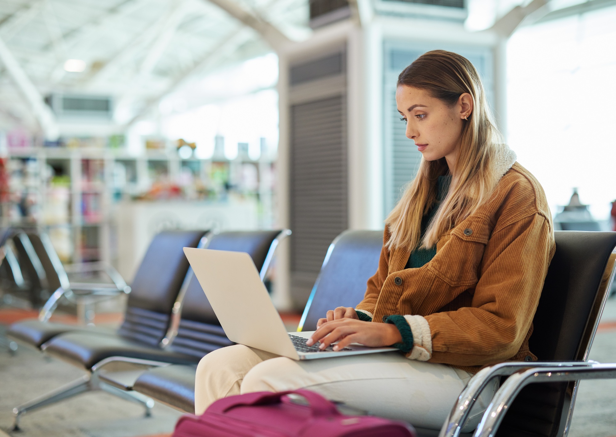 Airport, travel and woman typing on laptop in lobby, social media or internet browsing. Immigration