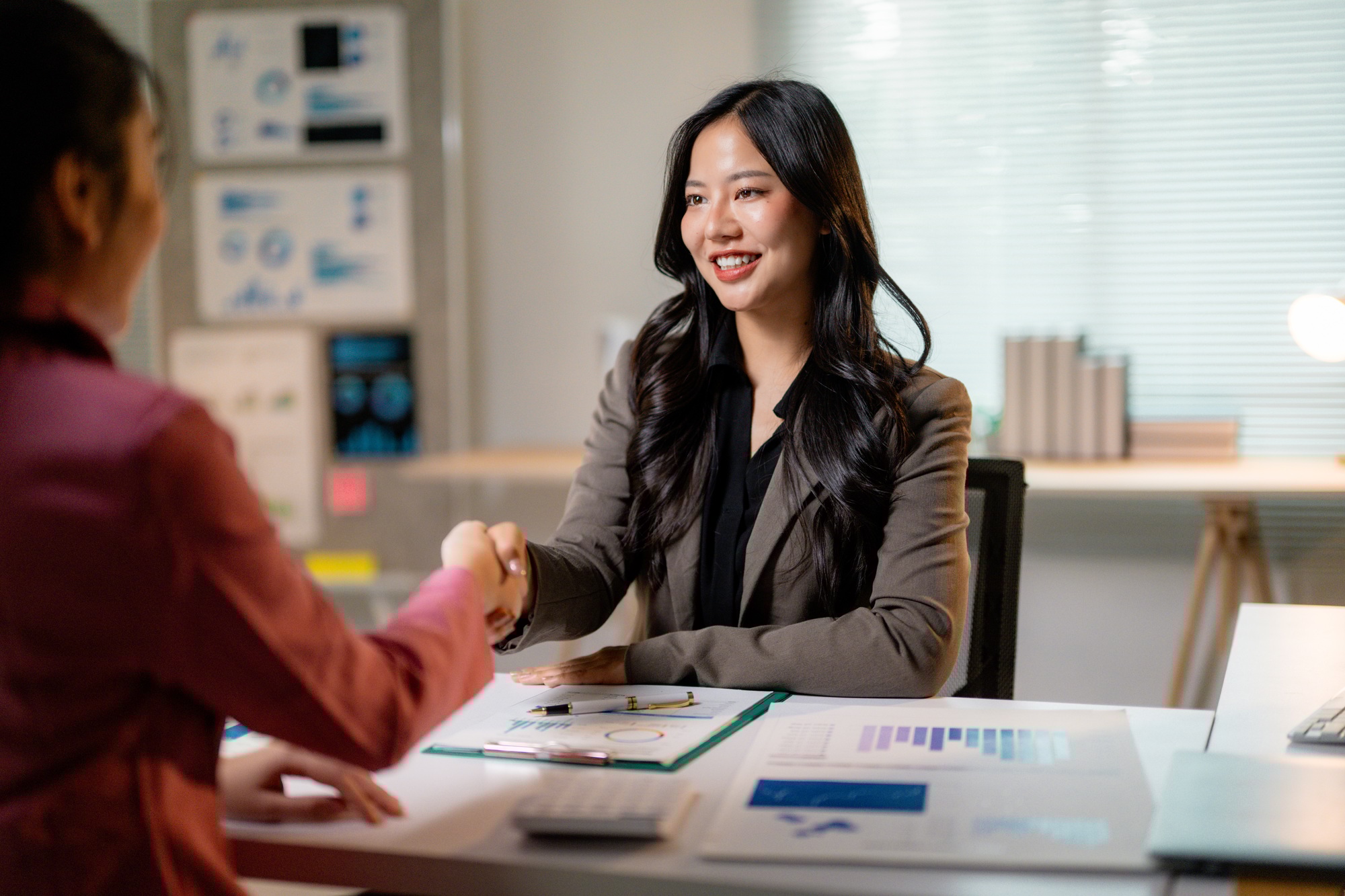 Businesswomen shaking hands after reaching an agreement during a business meeting in the office